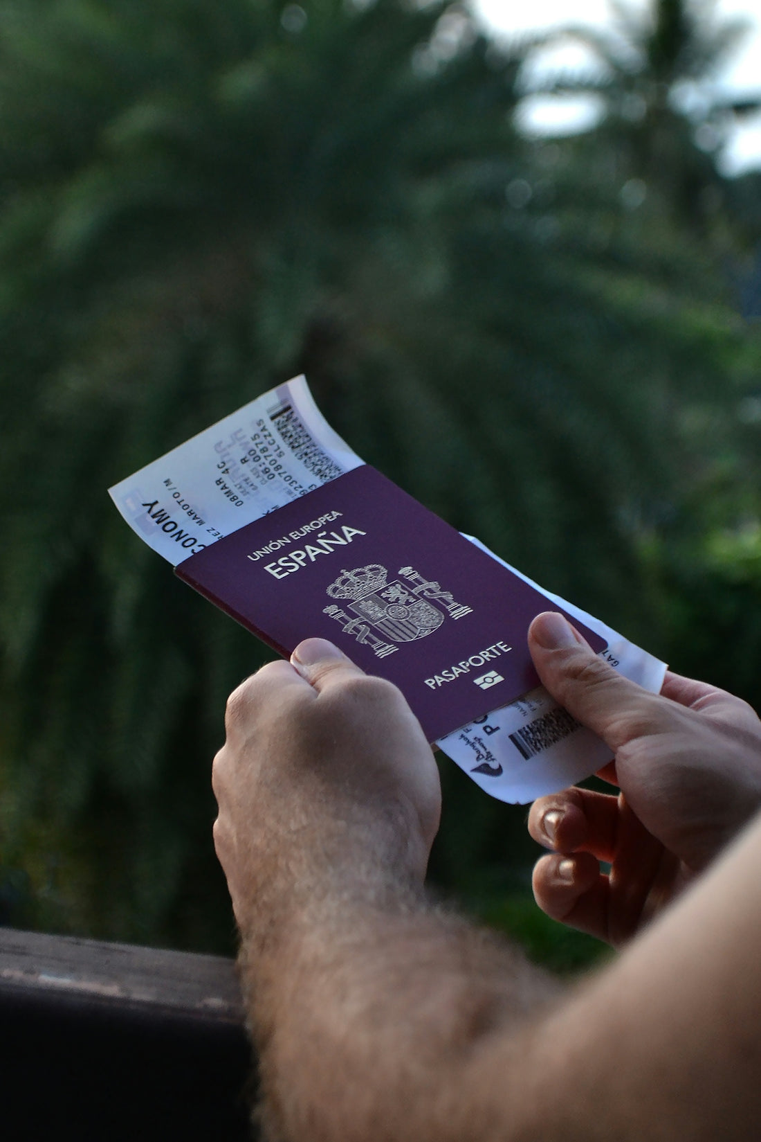 Spanish passport and boarding pass held by hands.