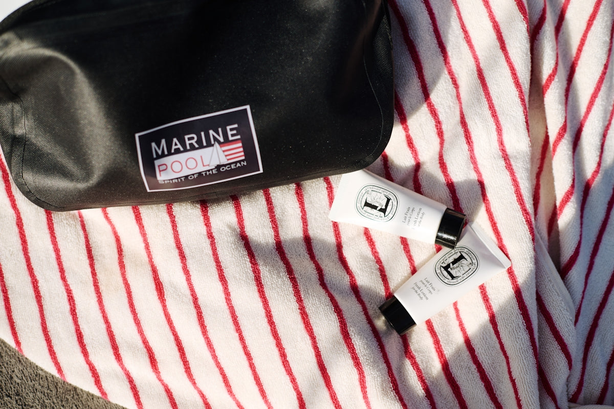 Cosmetic products and bag resting on a striped towel.