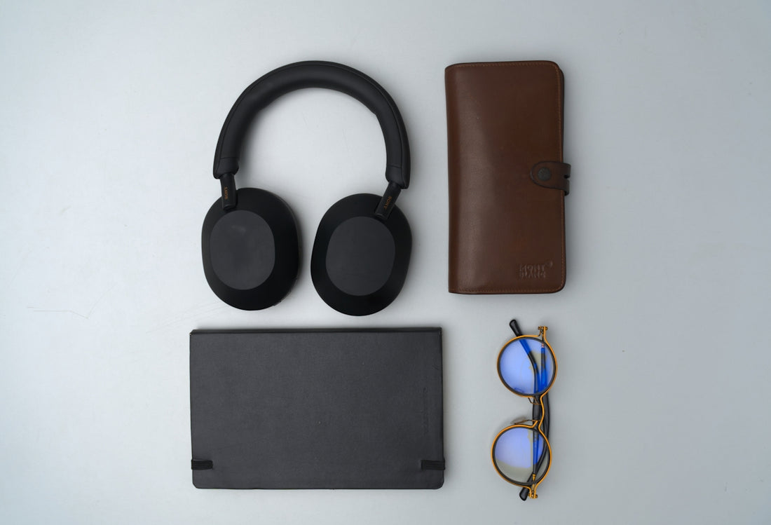 Black headphones, wallet, glasses, and tablet on gray