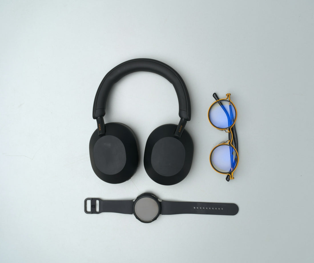 Black headphones, glasses, and smartwatch on gray background.