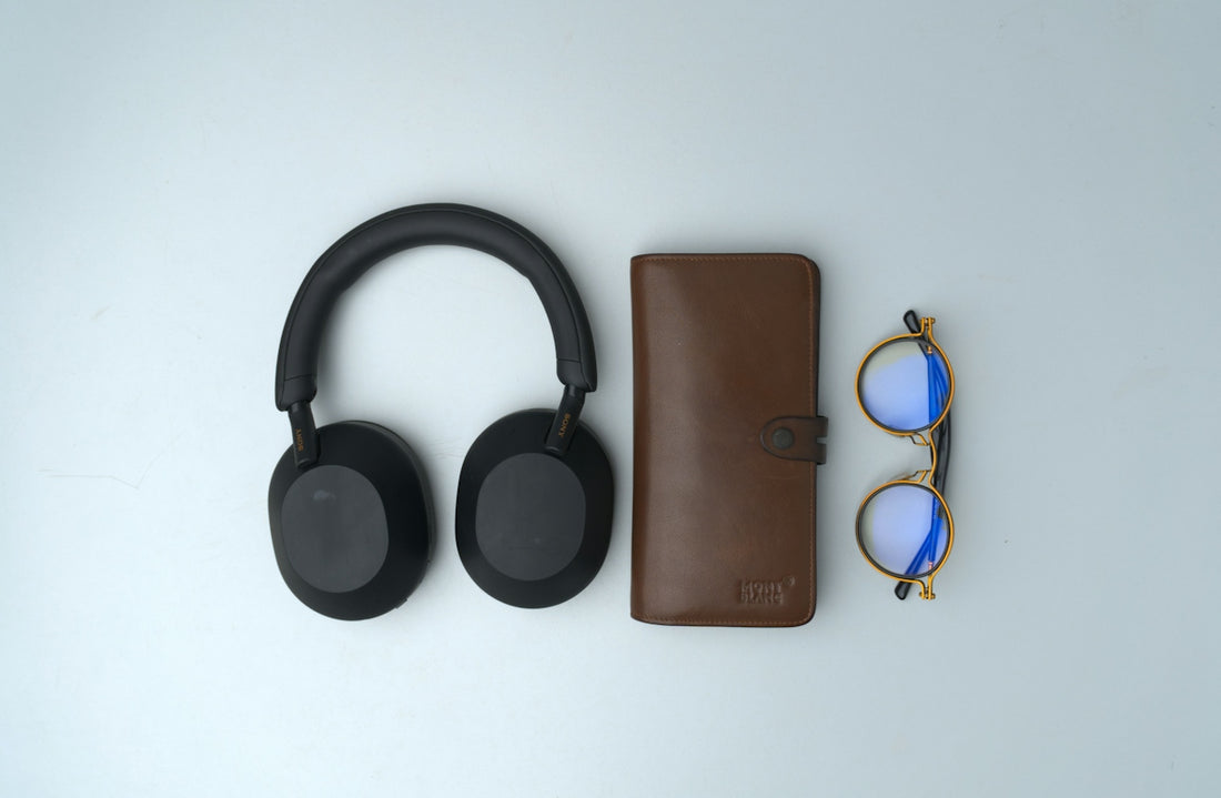 Black headphones, brown wallet, and glasses arranged neatly