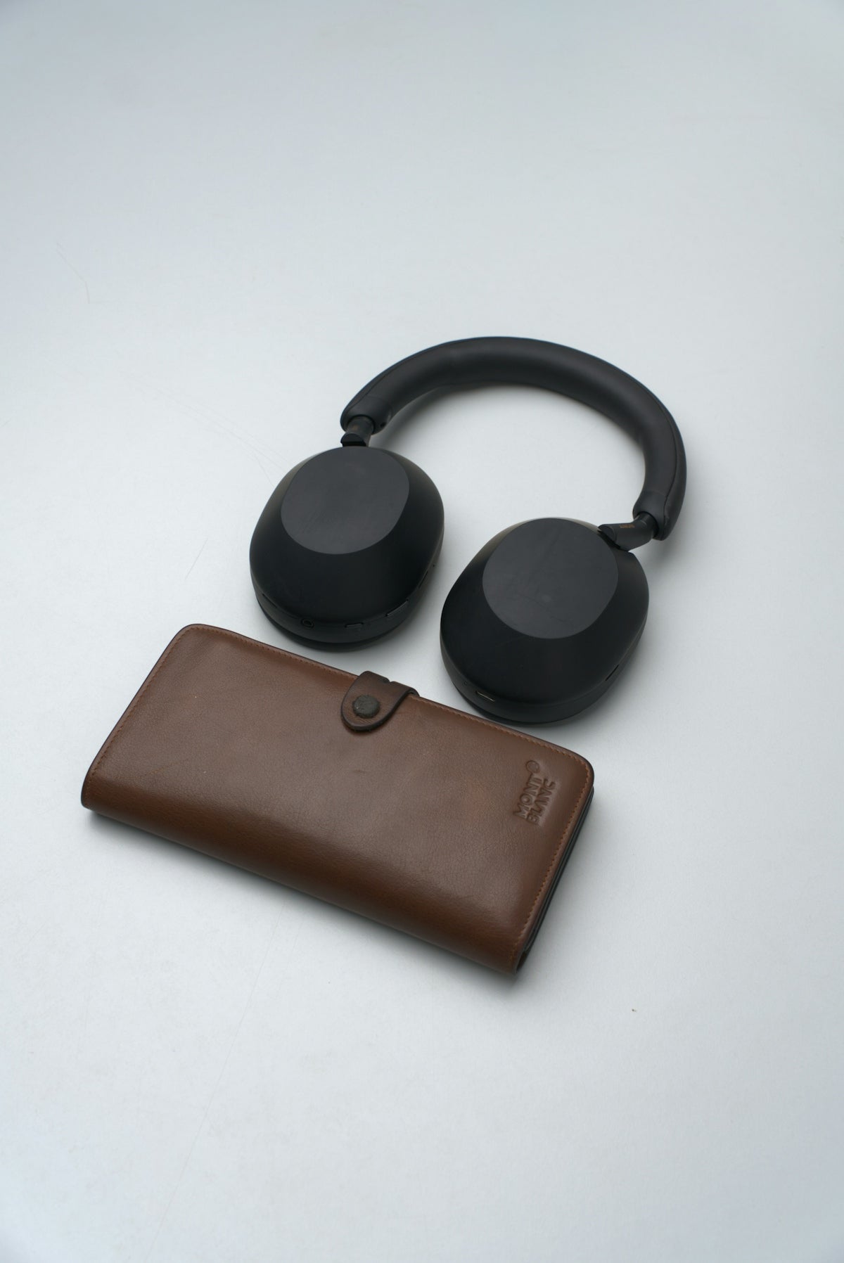 Black headphones and brown leather wallet on white background
