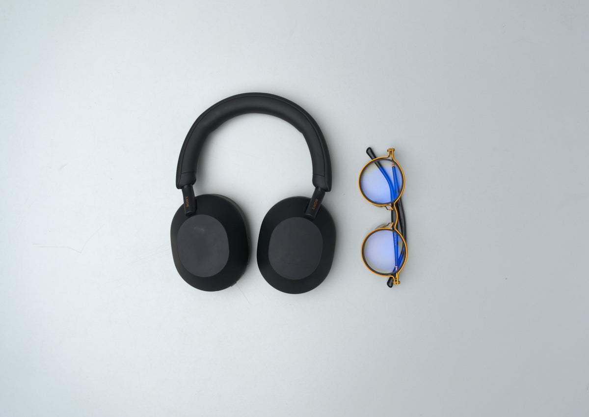 Black headphones and glasses on a light background