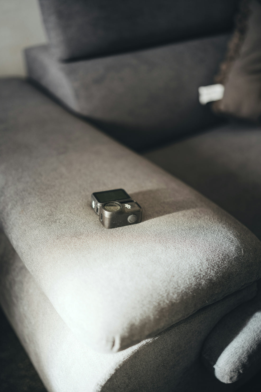 Small camera rests on a textured gray sofa.