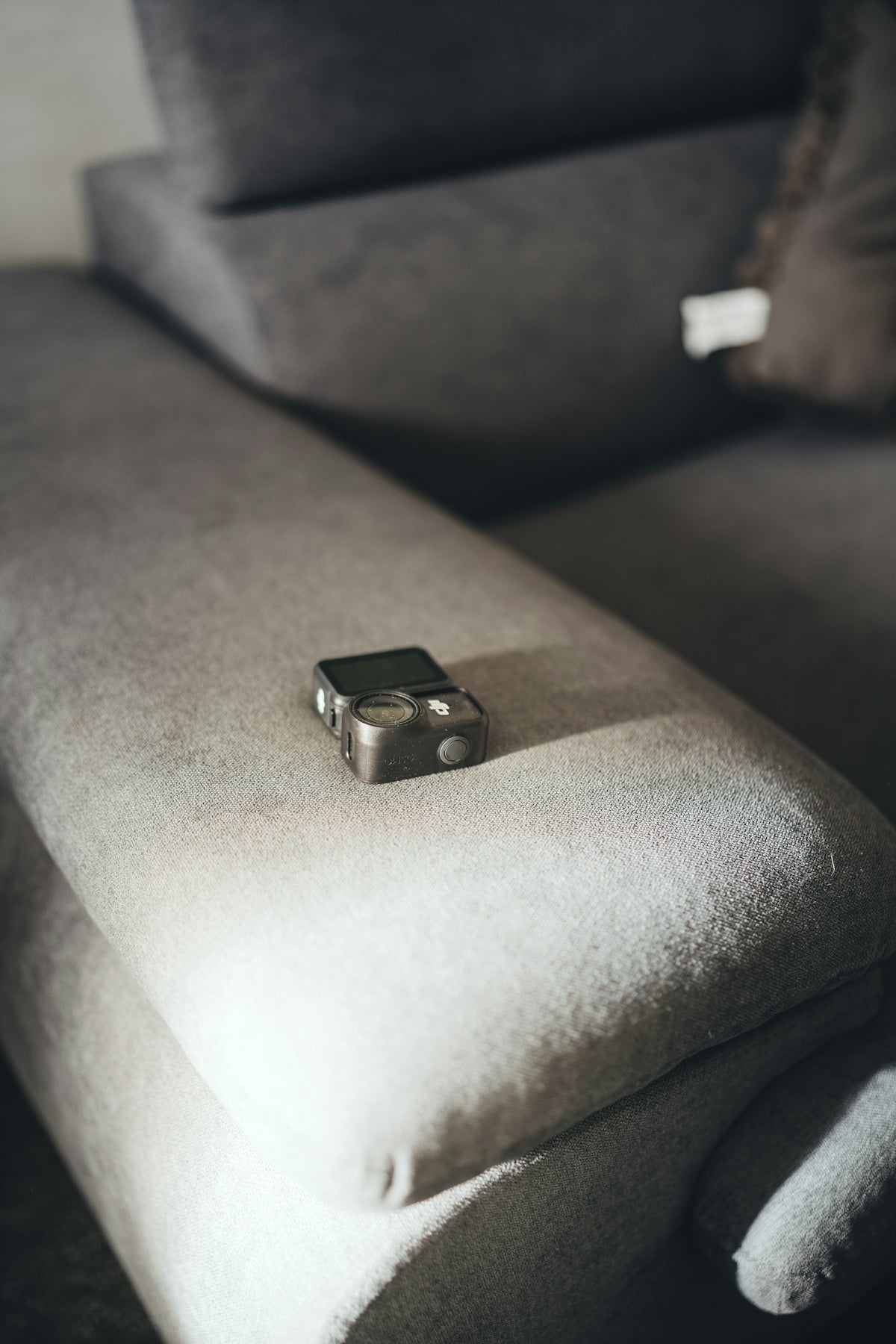 Small camera rests on a textured gray sofa.