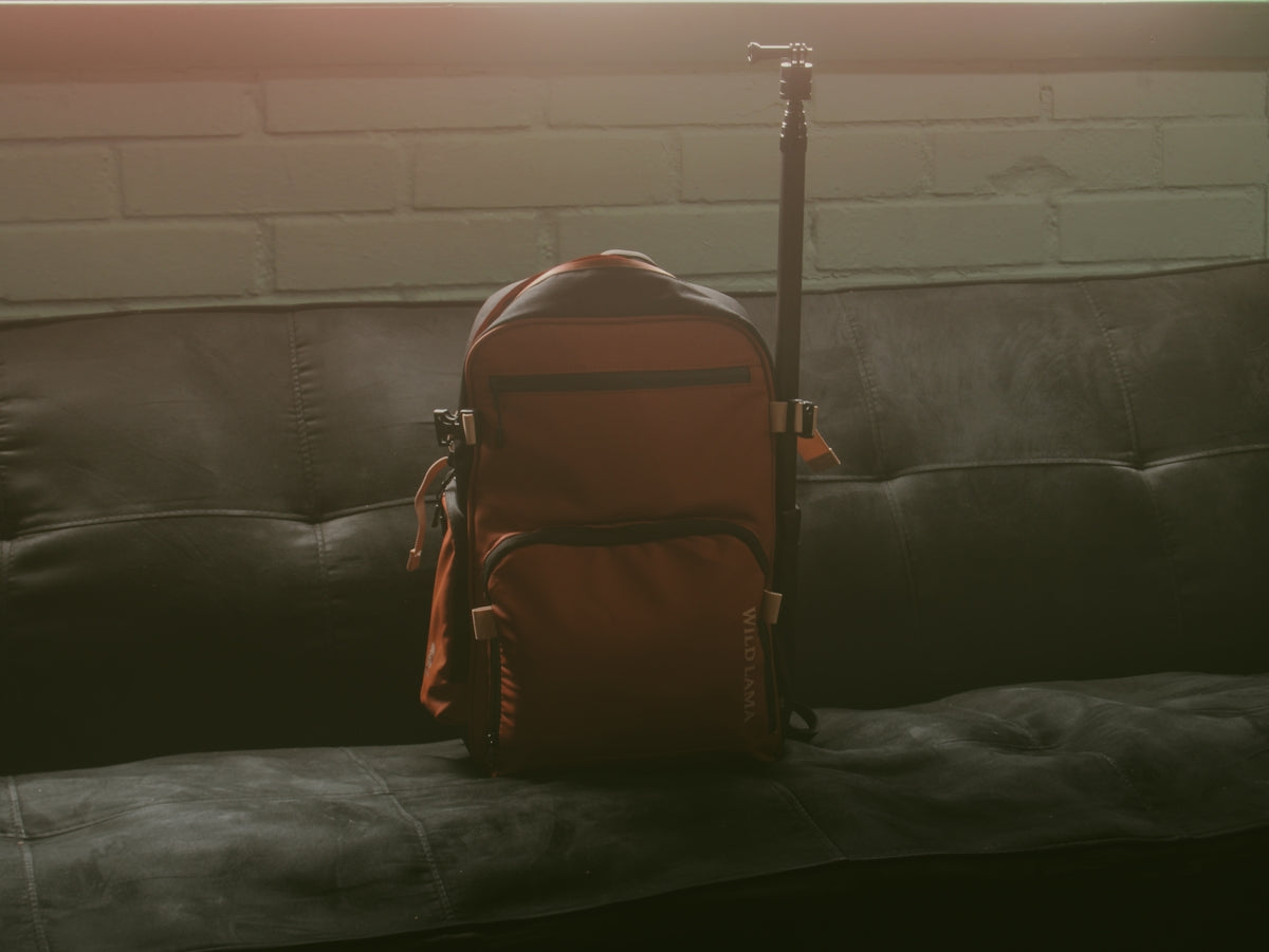 An orange backpack with a tripod on a couch