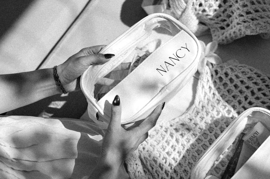 Hands holding a clear cosmetic bag with nancy label.