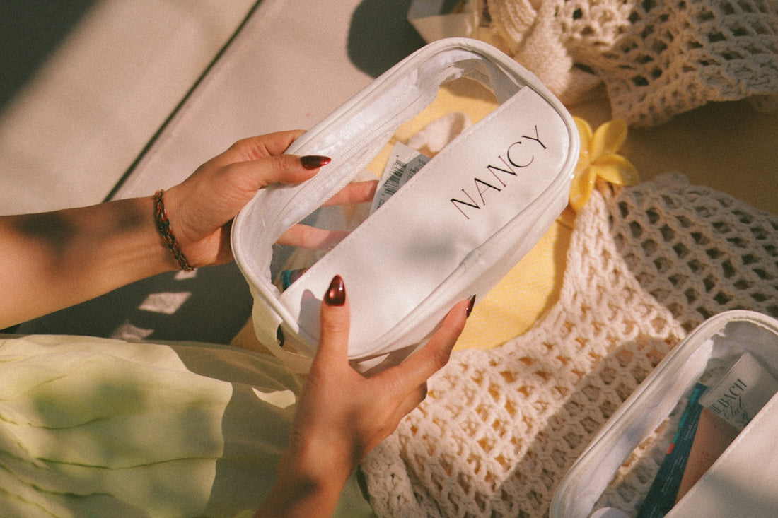 Hands holding a clear cosmetic bag with nancy label