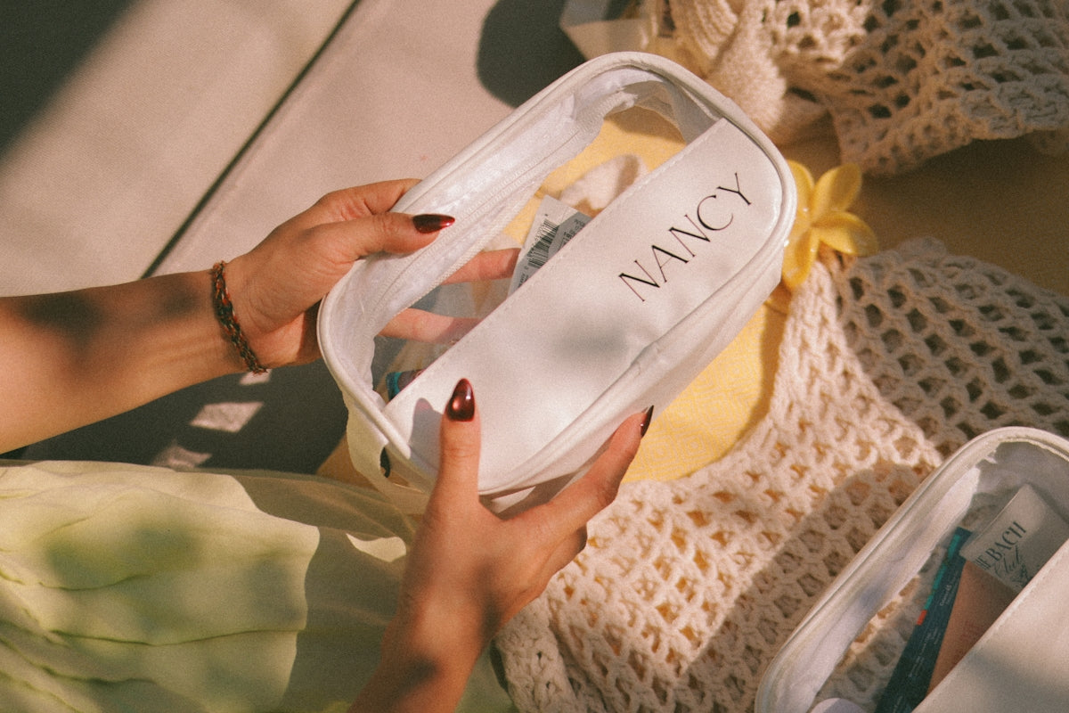 Hands holding a clear cosmetic bag with nancy label