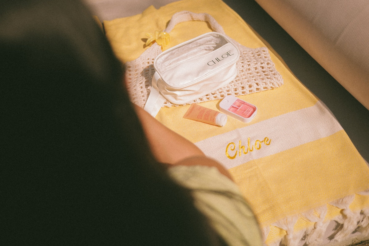 Yellow towel with toiletries and makeup bag on it