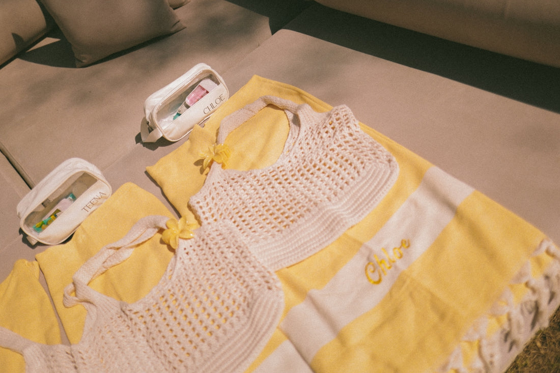 Two white crochet tops on a yellow striped towel.