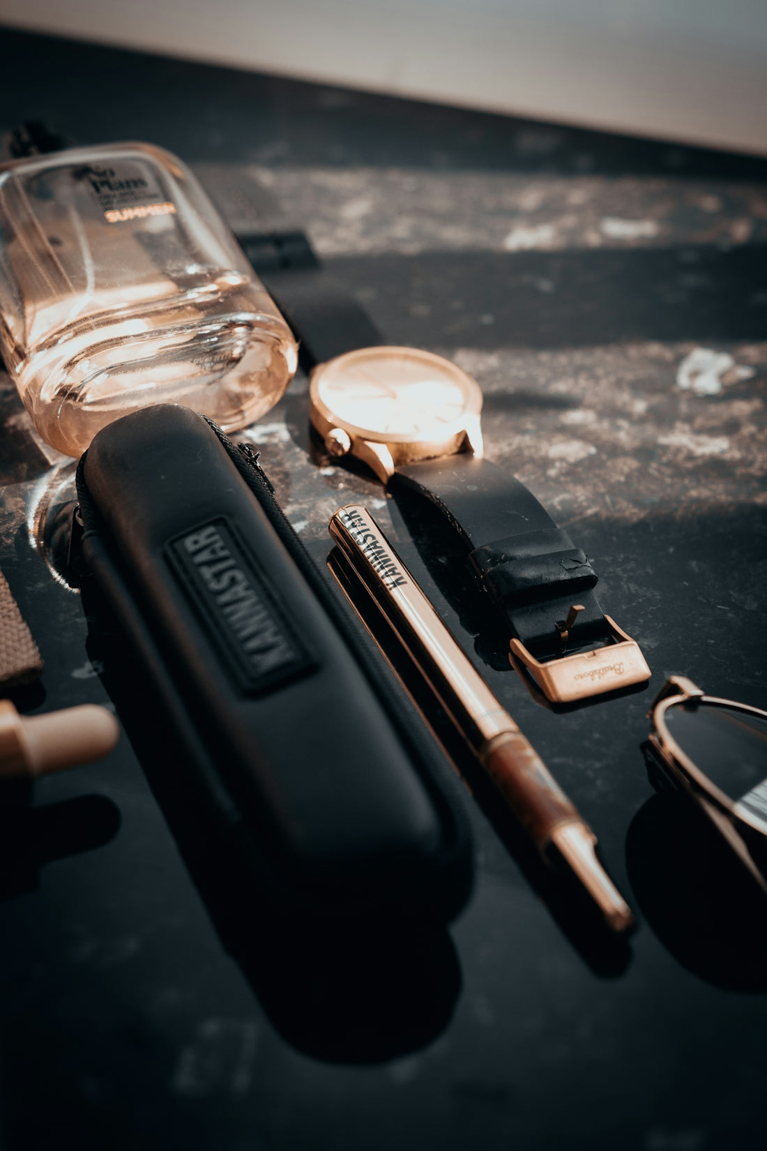 A collection of men's accessories on a dark surface.