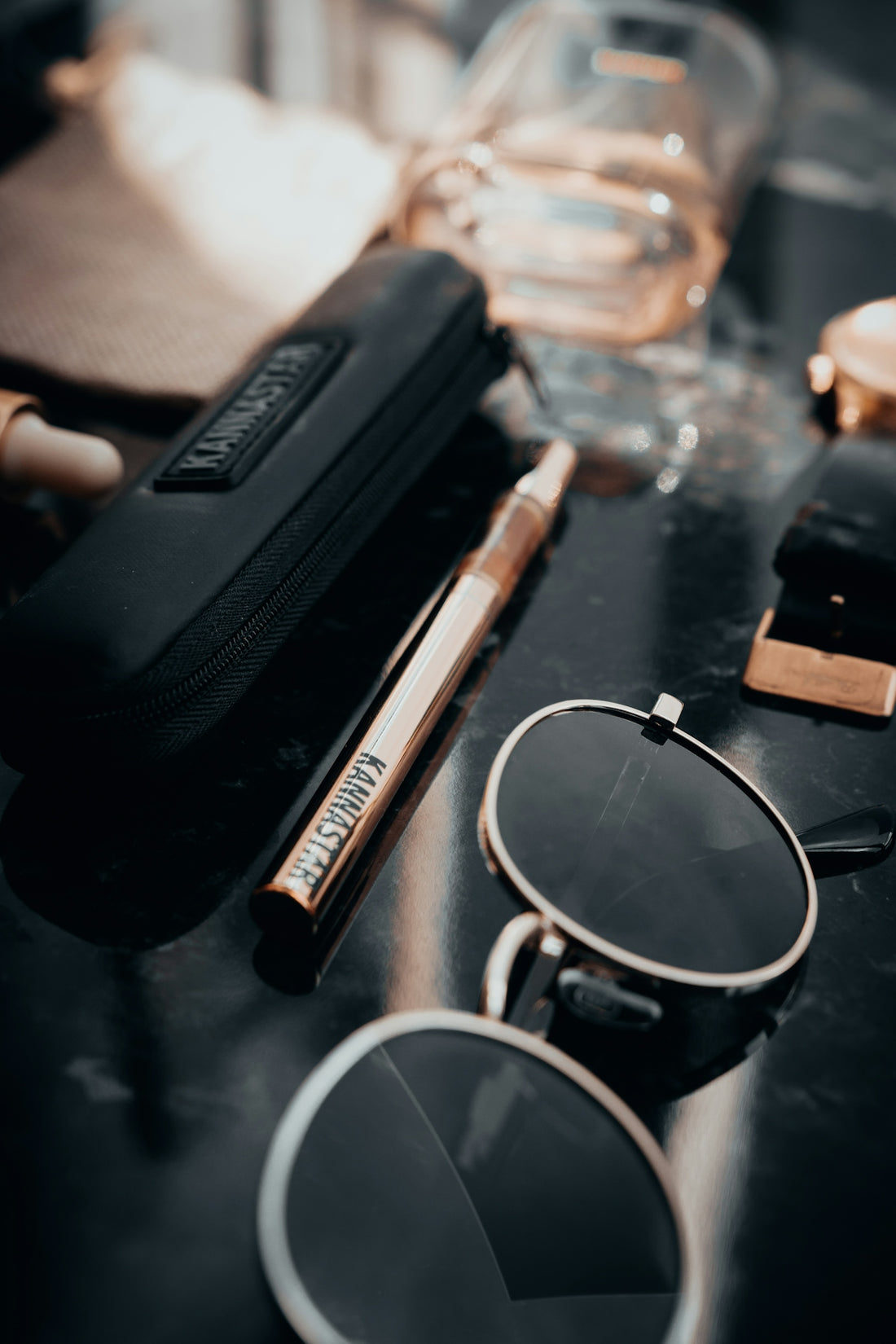 Sunglasses, vape pen, and watch on table