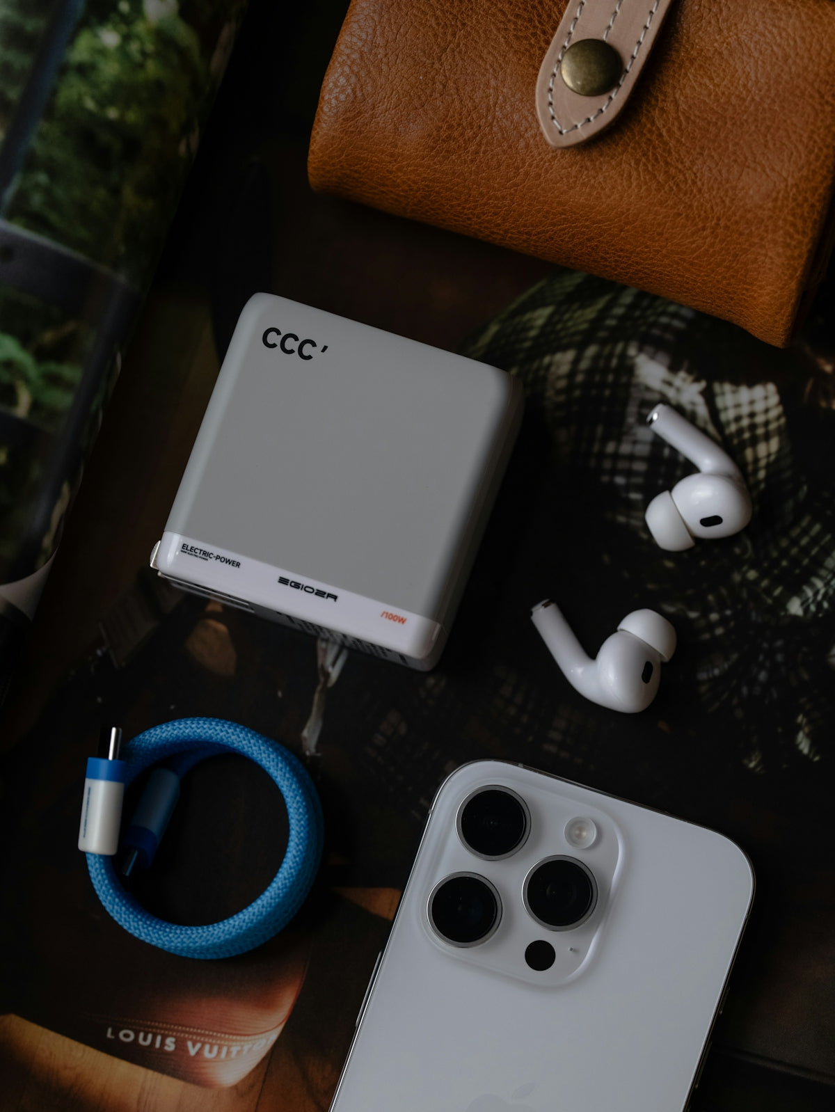 Smartphone, power bank, wireless earbuds, and wallet on surface.