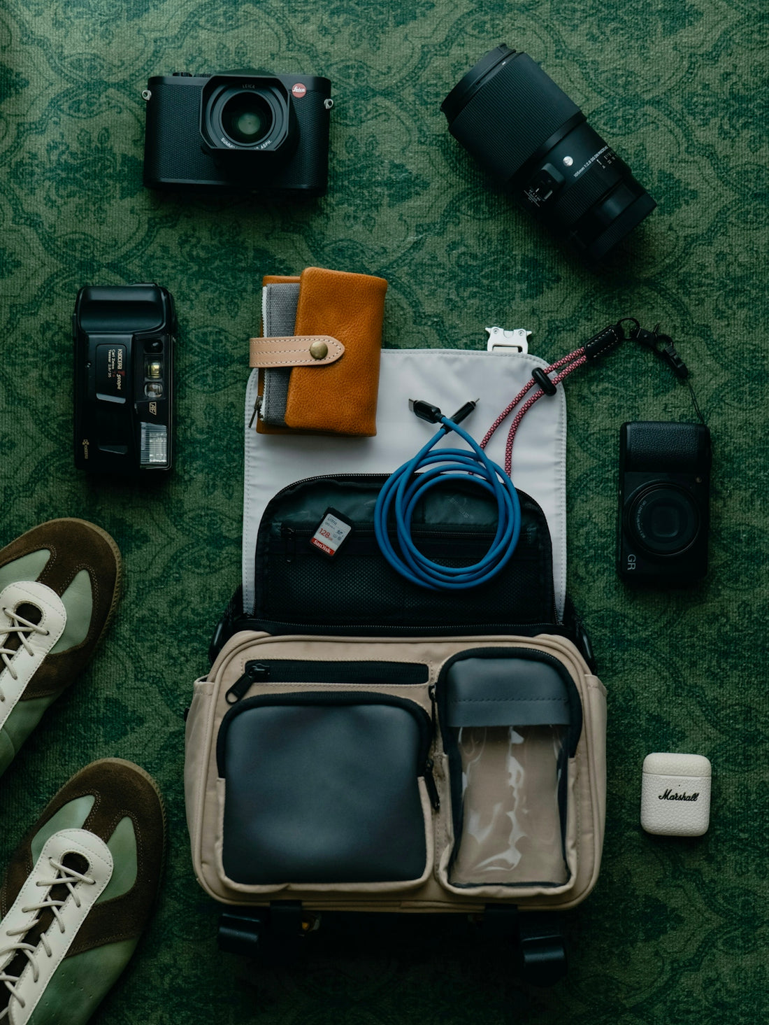 Camera gear and accessories laid out on a patterned surface.