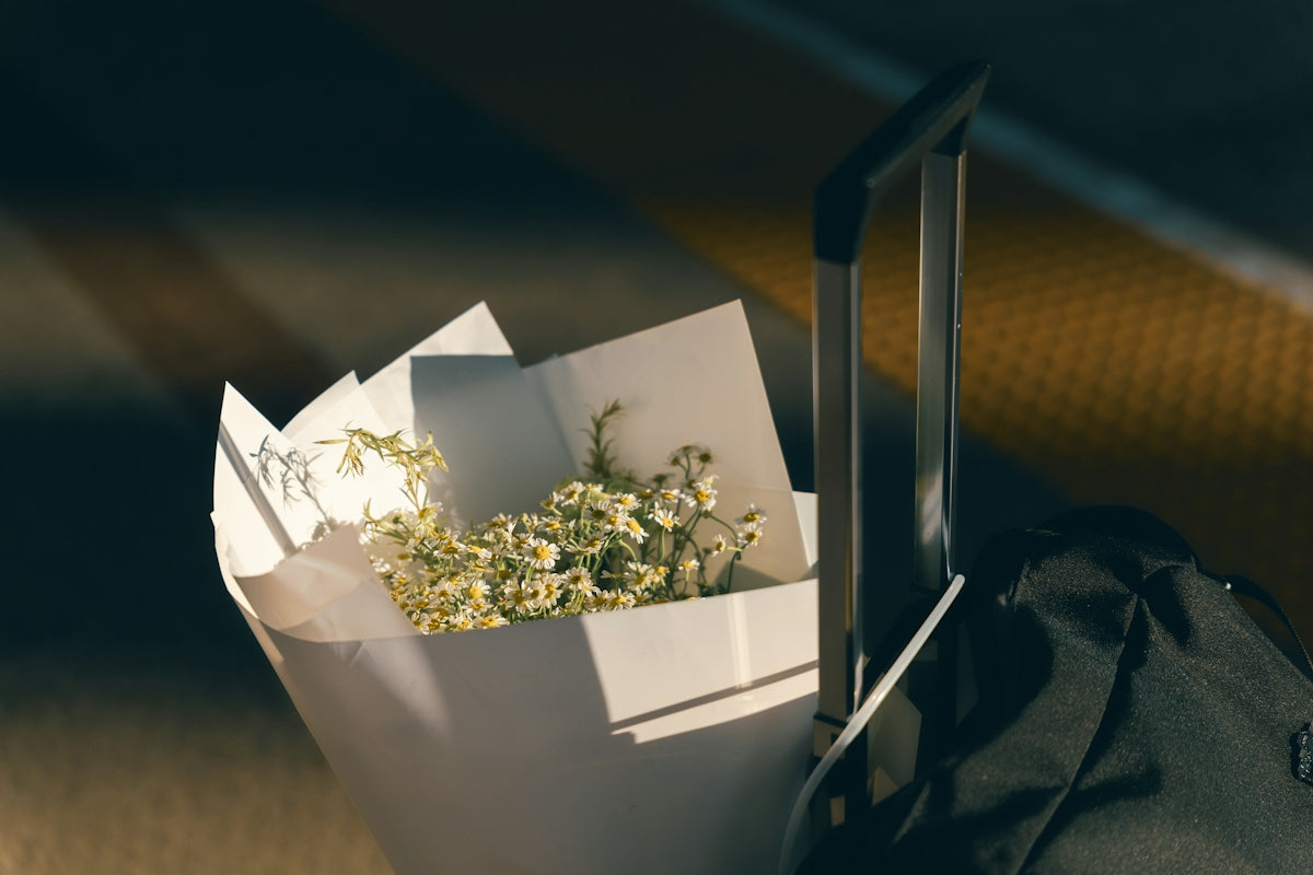 A bouquet of dried flowers next to a black suitcase