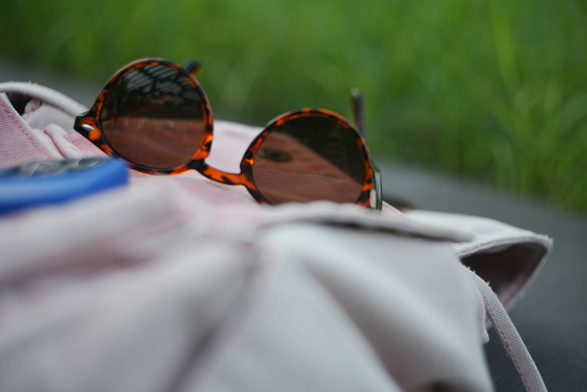 Tortoiseshell sunglasses resting on pink fabric with green background.
