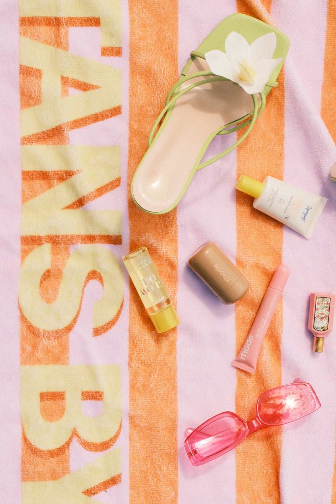 Beach accessories and green sandal on striped towel