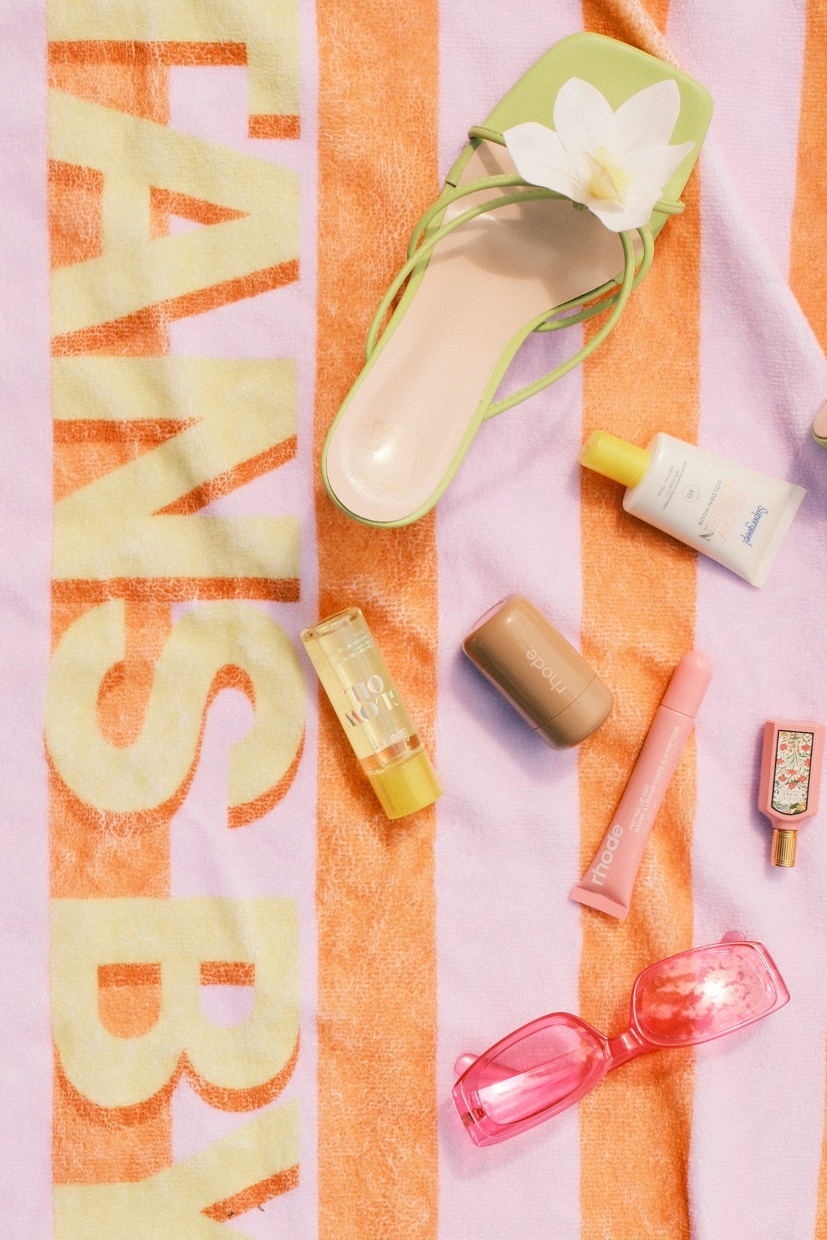 Beach accessories and green sandal on striped towel